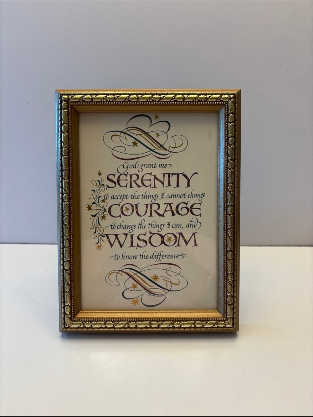 framed print of the Serenity Prayer in an ornate gold-colored frame.